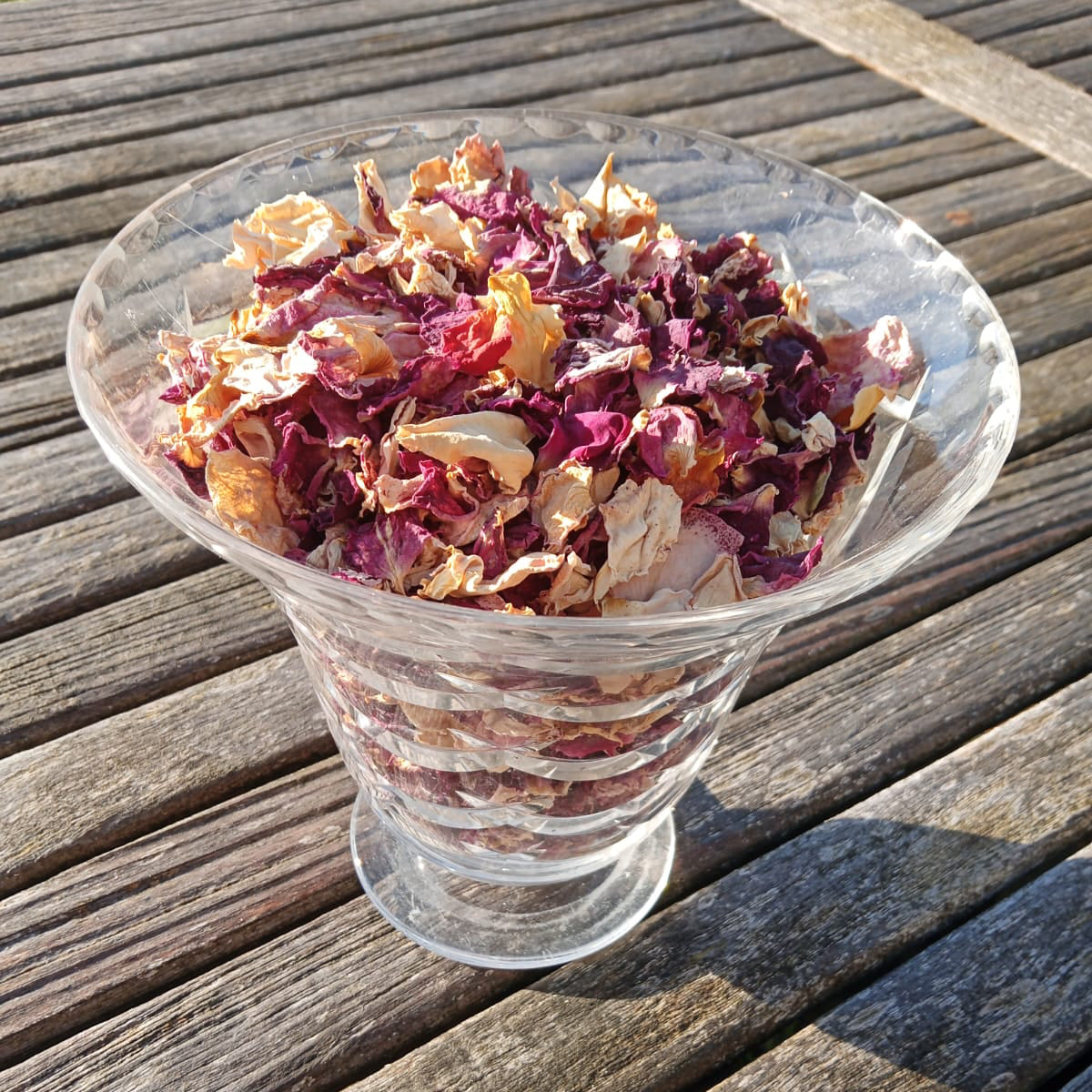 Clear glass bowl filled with dried flowers on a wooden surface